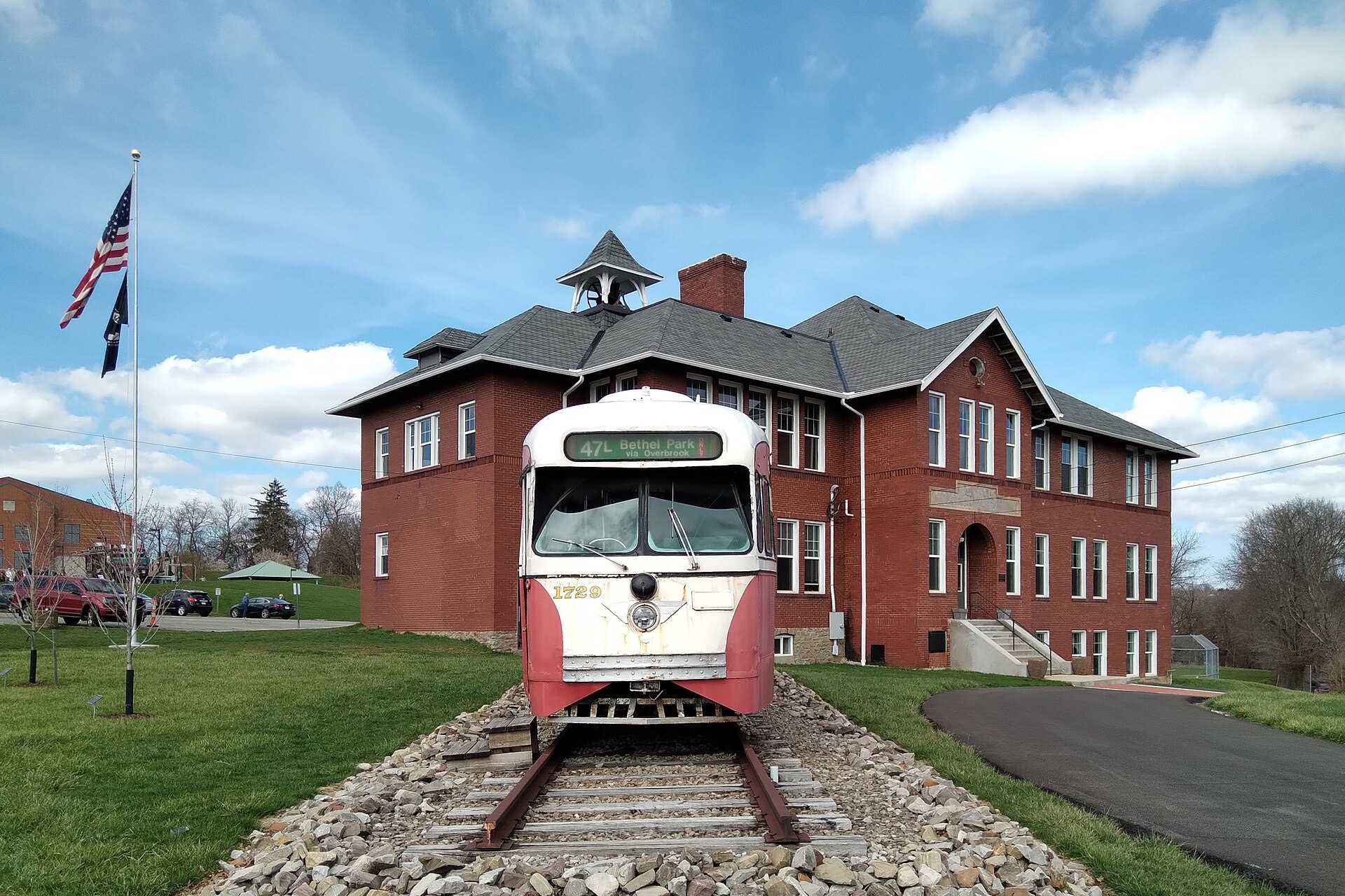 The historic Schoolhouse Arts & History Center in Bethel Park with a vintage Pittsburgh streetcar in front